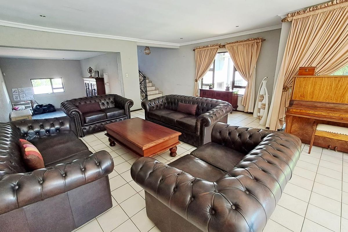 Spacious living room featuring tiled flooring, coved ceilings, and an open-plan layout leading to a staircase area.