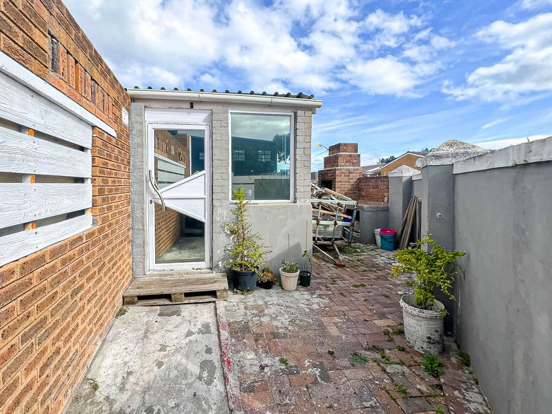 Outdoor patio area featuring brick paving, a built-in braai, and a rear entrance door, offering potential for a refreshed entertainment space.
