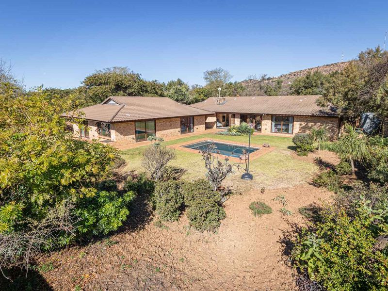 Rear view of a brick house featuring a swimming pool, landscaped garden, and sliding glass doors leading to the interior living spaces.