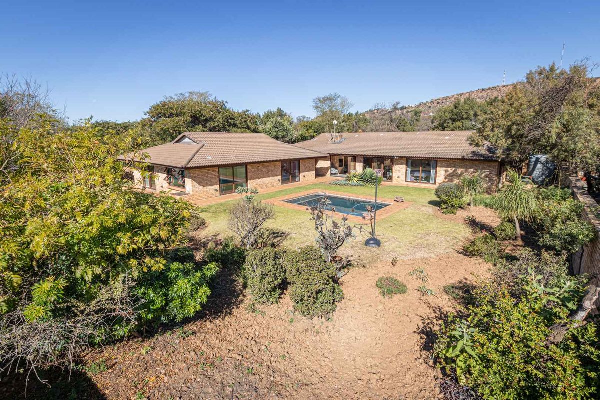 Rear view of a brick house featuring a swimming pool, landscaped garden, and sliding glass doors leading to the interior living spaces.