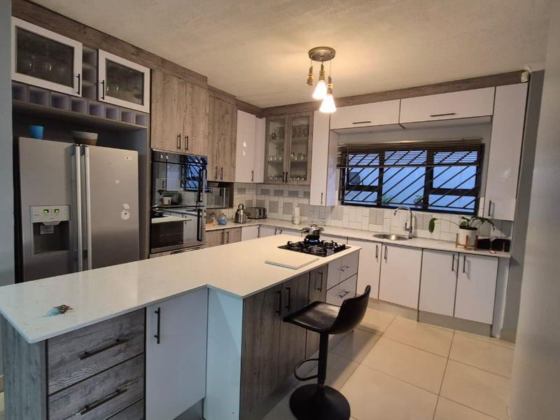 Modern kitchen featuring a central island, stone countertops, built-in oven, gas hob, and ample cabinetry with a clean, contemporary finish.