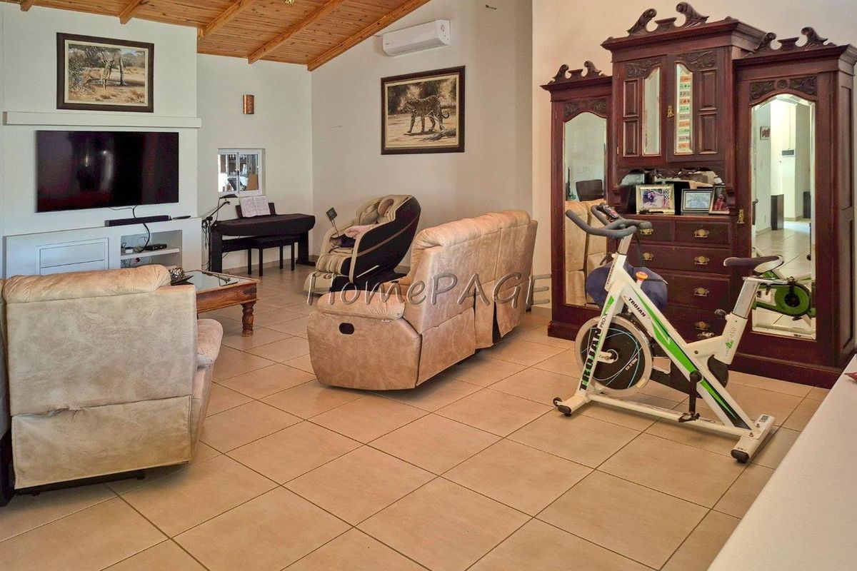 Spacious living area featuring tiled flooring, a timber-clad vaulted ceiling, and a wall-mounted air conditioning unit.
