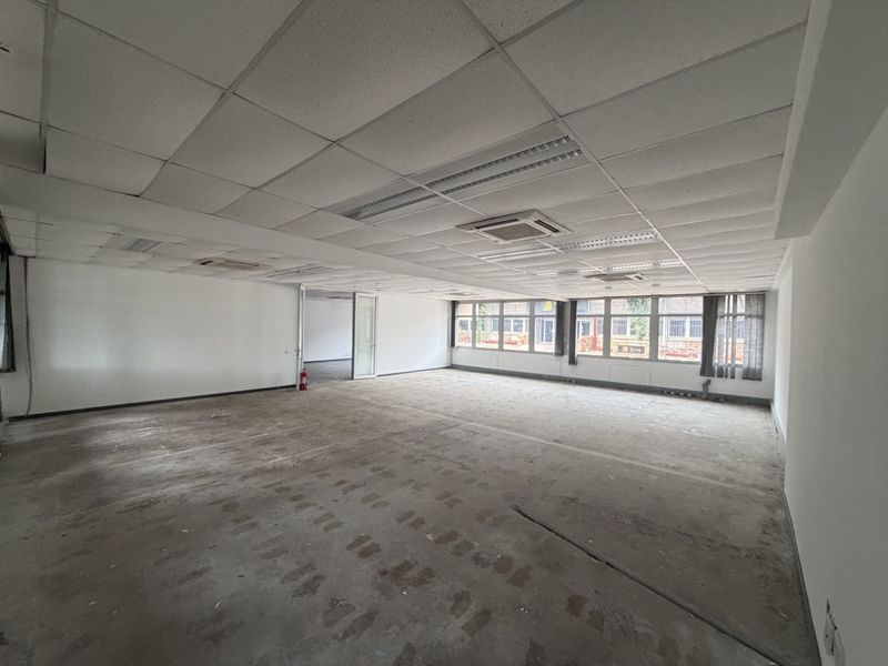 Spacious open-plan industrial office area featuring a suspended ceiling, integrated air conditioning, and large windows providing ample natural light.