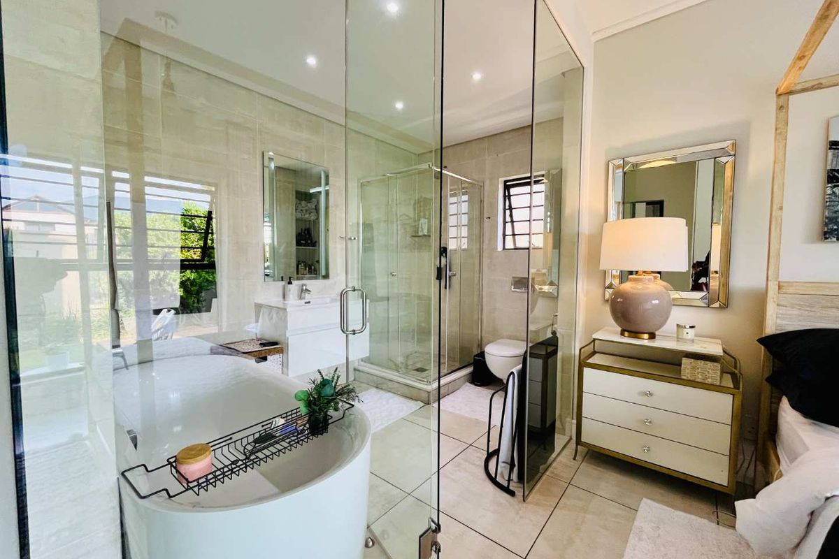 Modern en-suite bathroom featuring a sleek freestanding bathtub, glass-enclosed shower, wall-mounted toilet, and contemporary vanity, finished with high-quality tiling.
