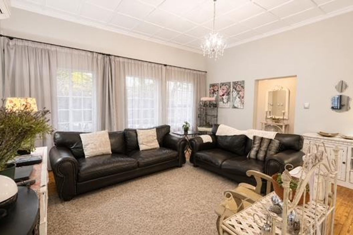Spacious living room featuring high coffered ceilings, polished hardwood flooring, and large windows that provide ample natural light.