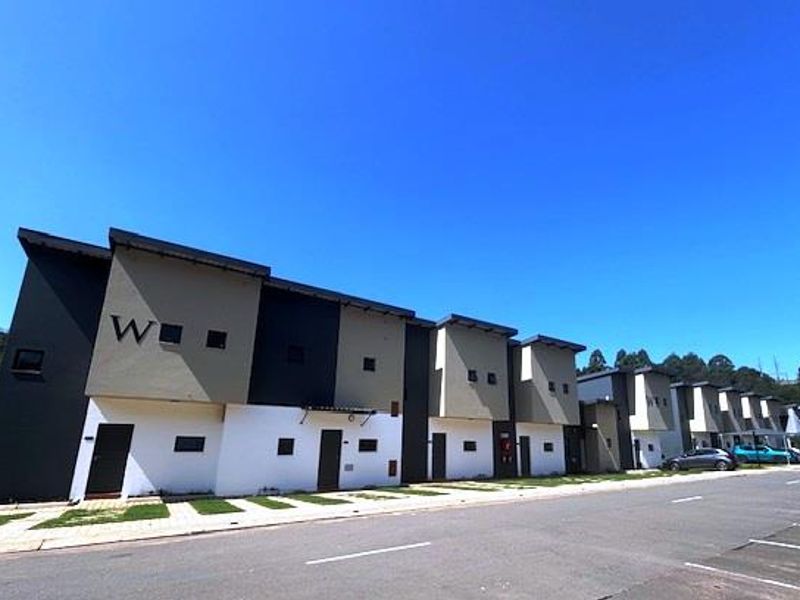 A street-level view of a modern townhouse complex featuring contemporary multi-tone facades and paved driveway access.