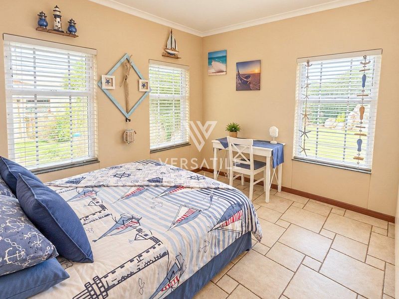 A bright bedroom featuring tiled flooring, built-in wardrobe storage, and multiple windows with venetian blinds, offering a clean and functional living space.