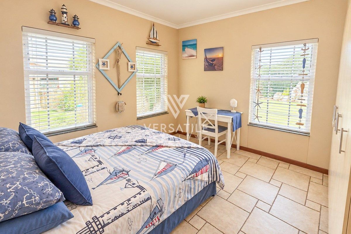 A bright bedroom featuring tiled flooring, built-in wardrobe storage, and multiple windows with venetian blinds, offering a clean and functional living space.