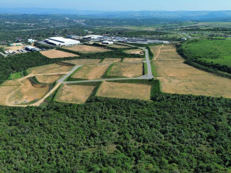 Aerial view of a large industrial development site featuring cleared land plots, paved access roads, and surrounding natural landscape.