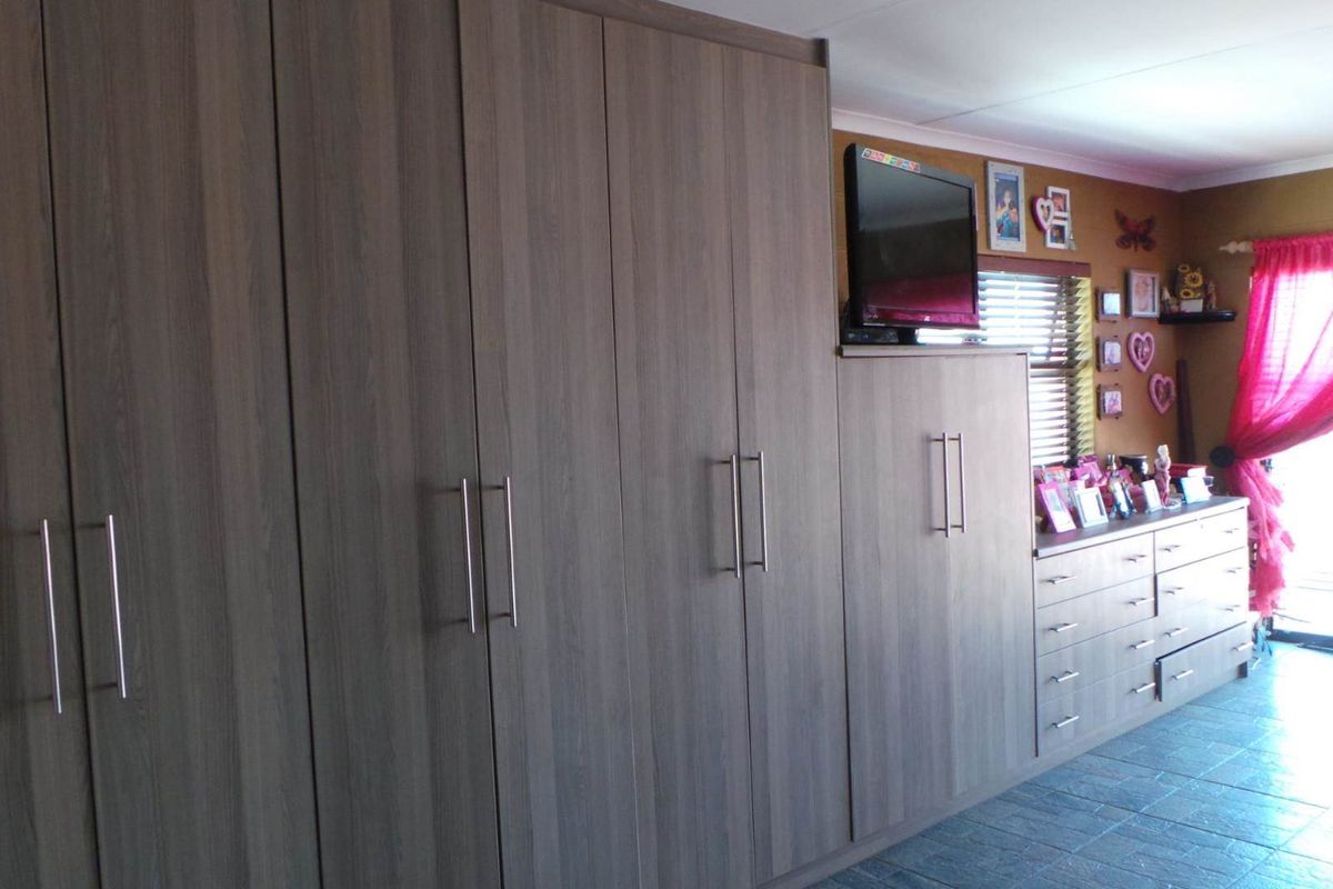 Bedroom featuring extensive built-in cabinetry with integrated storage and shelving, finished in a modern wood-grain laminate.