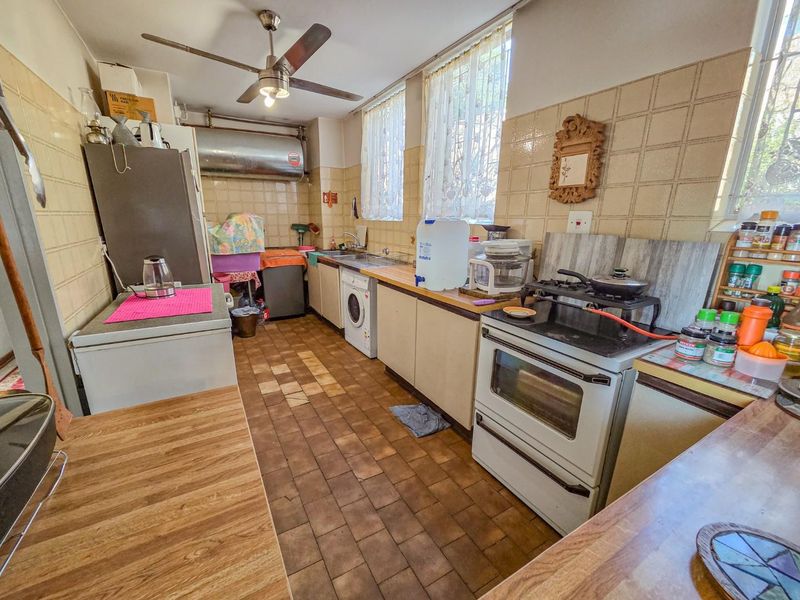 A functional kitchen featuring tiled walls, built-in cabinetry, a gas stove with oven, and a stainless steel sink.