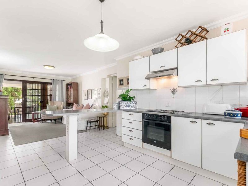 Open-plan kitchen and living area featuring white cabinetry, built-in appliances, tiled flooring, and direct access to an outdoor patio through sliding glass doors.