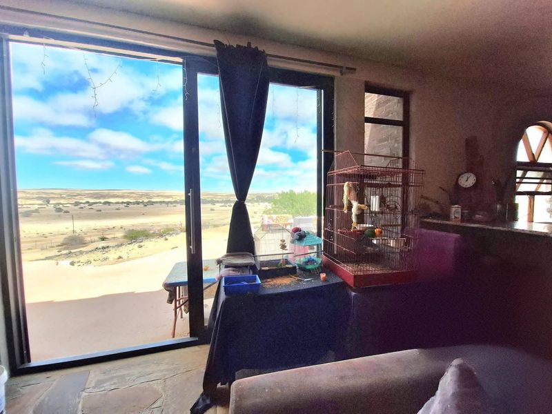 Living area featuring stone flooring and large sliding glass doors that provide expansive views of the surrounding landscape.