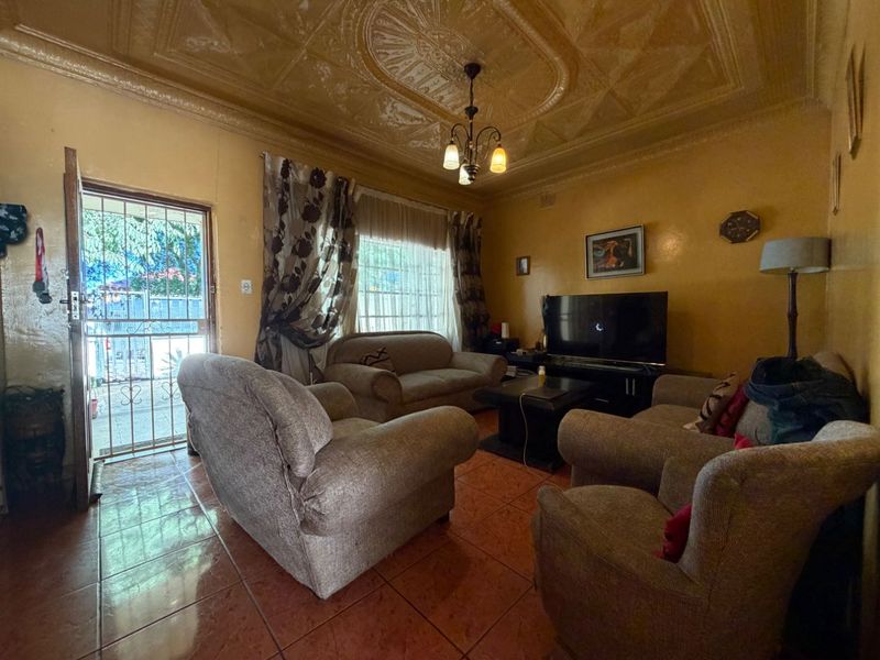 A living room featuring traditional pressed metal ceilings and tiled flooring, with direct access to the exterior through a security gate.