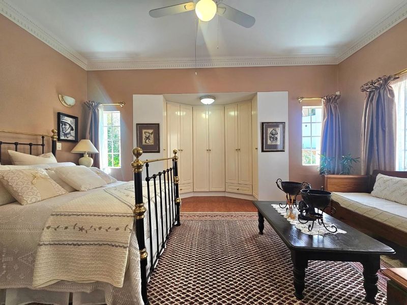 Spacious bedroom featuring built-in cupboards, decorative crown molding, and a ceiling fan, offering a comfortable and well-maintained living space.