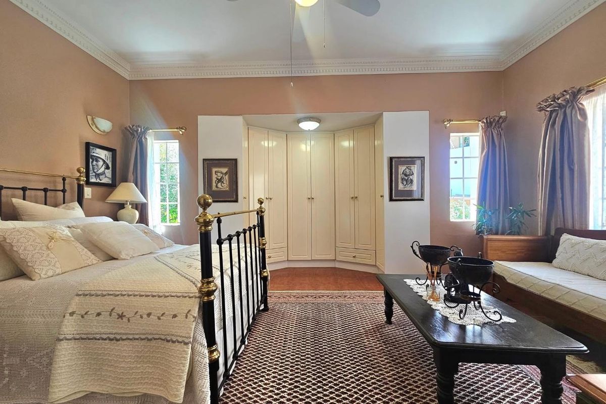 Spacious bedroom featuring built-in cupboards, decorative crown molding, and a ceiling fan, offering a comfortable and well-maintained living space.