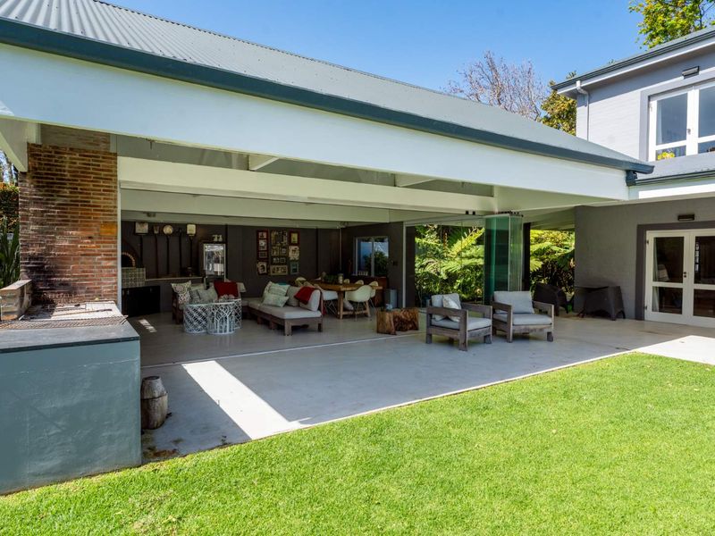 Spacious covered patio featuring a built-in braai, concrete flooring, and seamless stacking glass doors that open to the garden.
