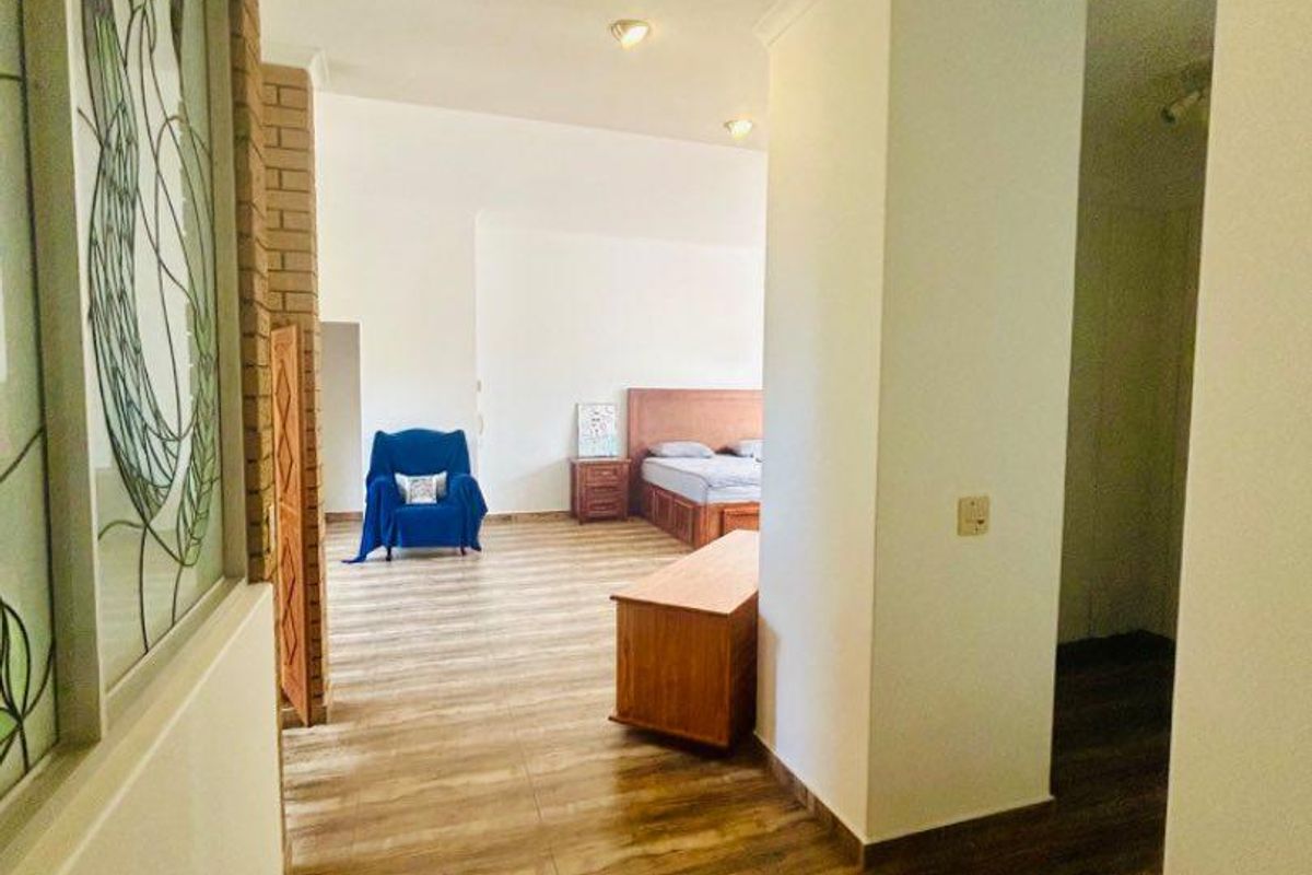 Spacious bedroom area featuring wood-look tile flooring, decorative stained glass window panel, and recessed ceiling lighting.