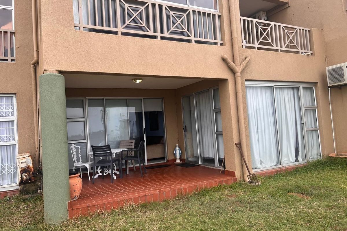Ground floor patio area with tiled flooring and sliding glass doors, featuring an upper-level balcony and exterior building facade.