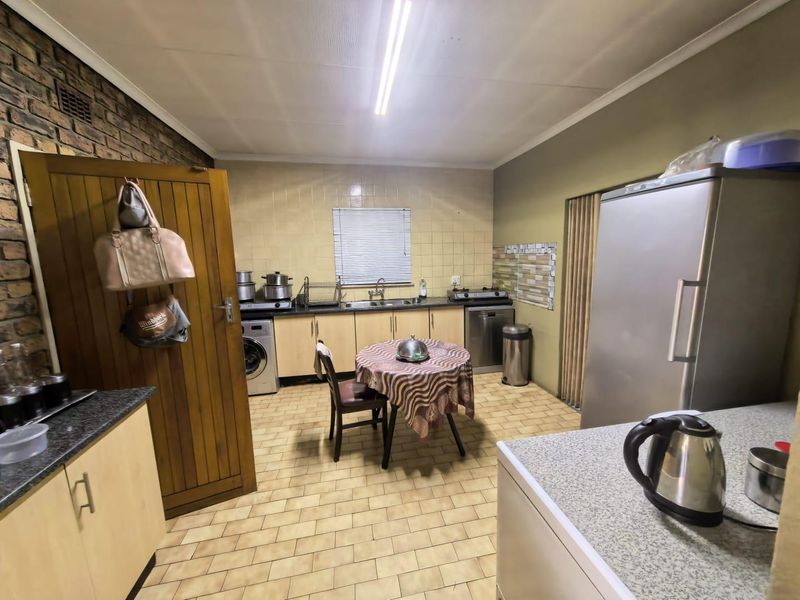 Functional kitchen featuring built-in cabinetry, laminate countertops, a tiled backsplash, and durable ceramic floor tiles with an exposed brick feature wall.