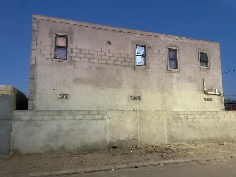 Exterior view of a multi-story residential building featuring an unfinished concrete block facade and aluminium windows.