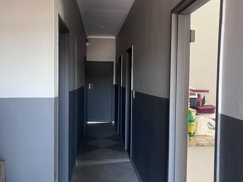 A functional hallway featuring tiled flooring and a two-tone painted wall finish, providing access to multiple rooms within the home.