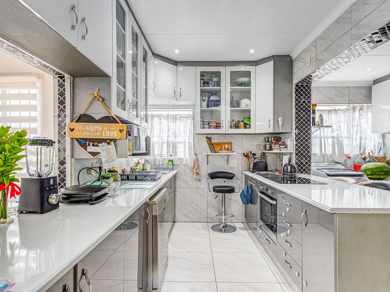 A modern, well-maintained kitchen featuring sleek cabinetry, stone countertops, integrated appliances, and high-quality tiled finishes throughout.