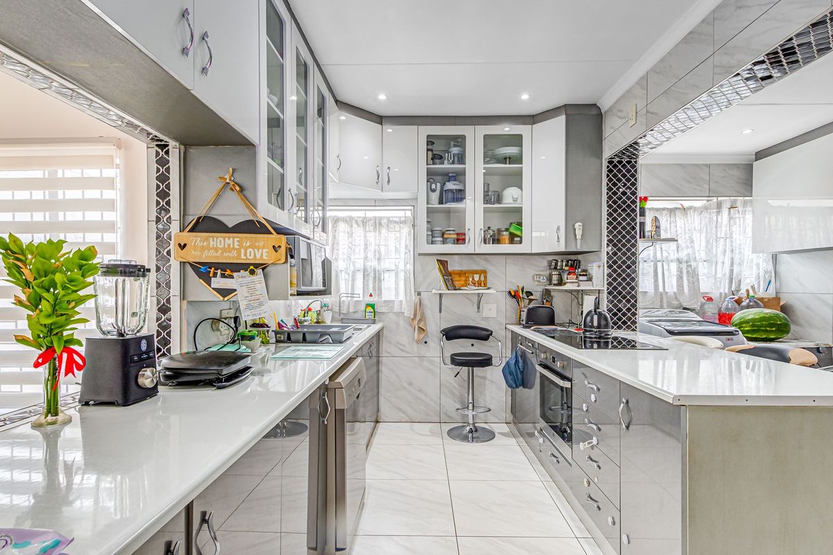 A modern, well-maintained kitchen featuring sleek cabinetry, stone countertops, integrated appliances, and high-quality tiled finishes throughout.