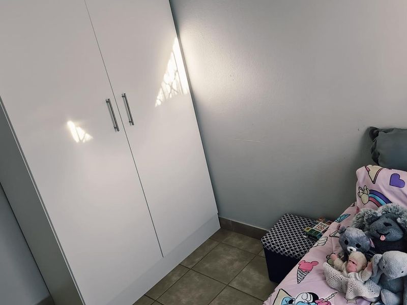 A bedroom featuring a white built-in wardrobe and tiled flooring.