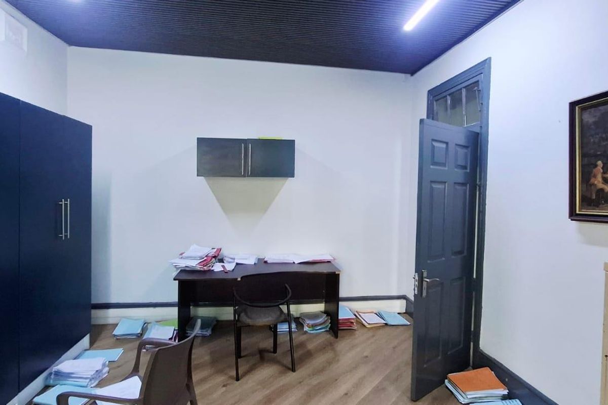 A functional office space featuring built-in dark cabinetry, laminate flooring, and a distinctive corrugated ceiling, suitable for a professional work environment.