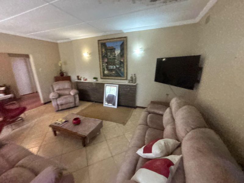 A living room featuring tiled flooring, wall sconces, and built-in shelving, showing visible signs of ceiling water damage.