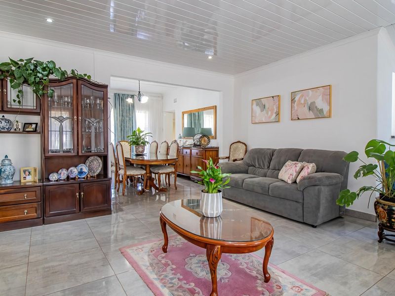 Spacious open-plan living and dining area featuring glossy tiled flooring and a modern white panelled ceiling with recessed lighting.
