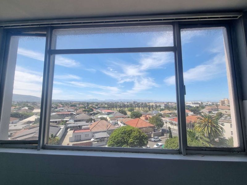 A clear elevated view of the surrounding residential neighbourhood and distant mountains, framed by a large aluminium window.