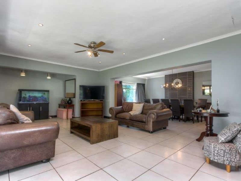 Spacious open-plan living and dining area featuring tiled flooring, recessed lighting, a ceiling fan, and a tiled fireplace feature wall.