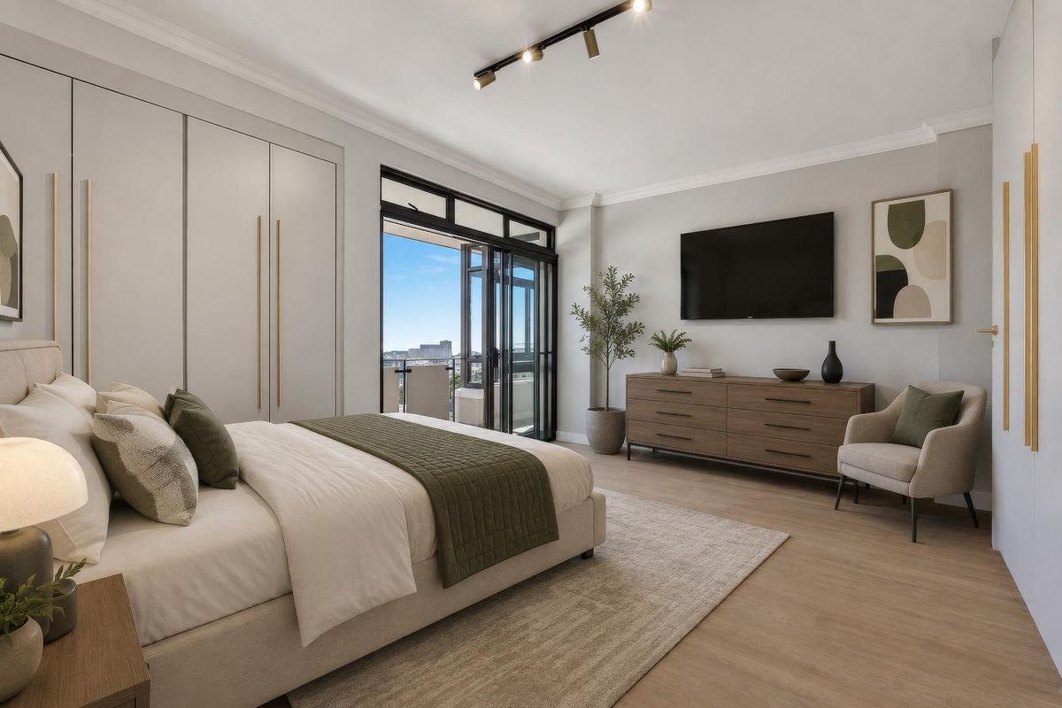 Modern bedroom featuring built-in wardrobes, sleek track lighting, crown molding, and direct access to a private balcony through sliding glass doors.