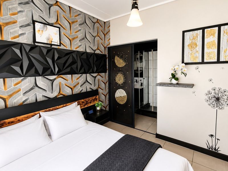 A modern bedroom featuring a decorative accent wall, tiled flooring, and direct access to an en-suite bathroom through a sliding door.