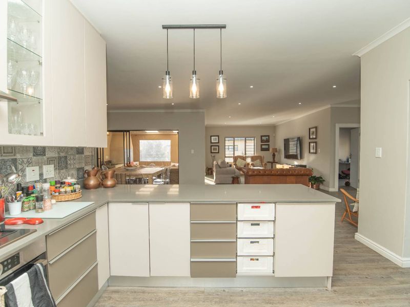 Modern open-plan kitchen featuring sleek cabinetry, stone countertops, and integrated appliances, flowing seamlessly into the spacious living and dining areas.