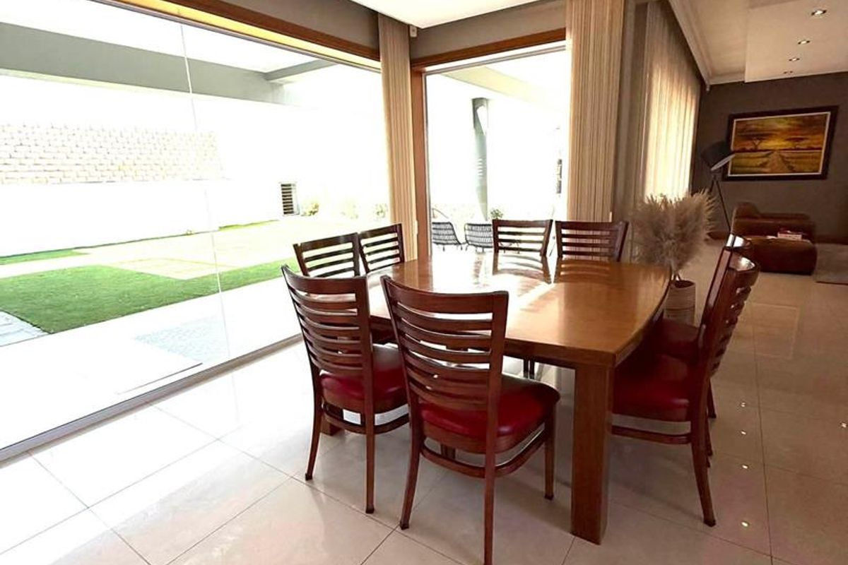 Bright dining area featuring large format floor tiles and expansive sliding glass doors that provide seamless access to the outdoor patio.