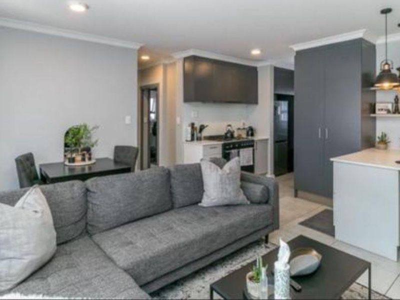 Modern open-plan living area featuring a contemporary kitchen with island, sleek cabinetry, and stylish pendant lighting, seamlessly integrated with the dining and lounge space.