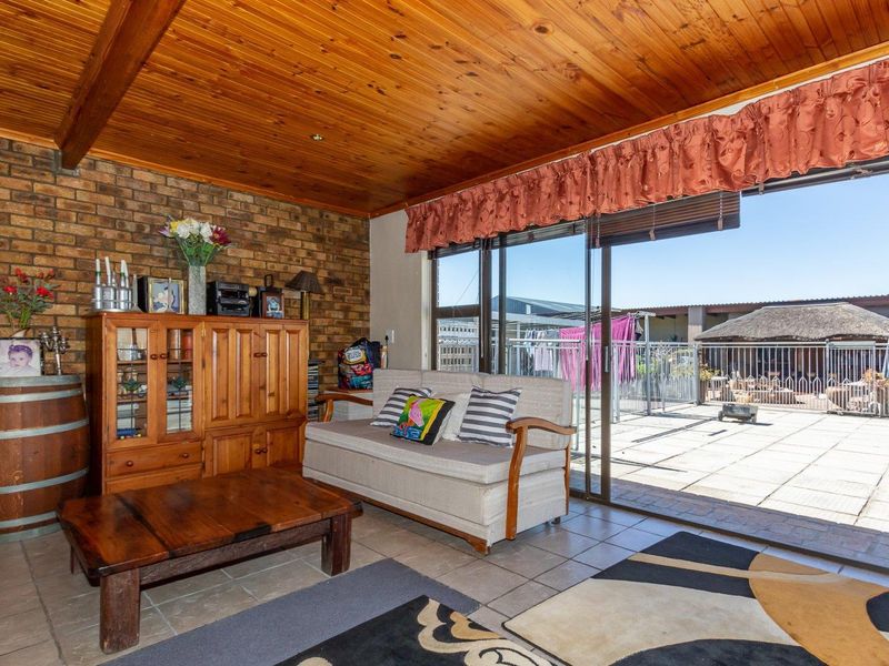 Living room featuring exposed brick walls, a timber-clad ceiling, and large sliding glass doors providing direct access to the outdoor patio area.
