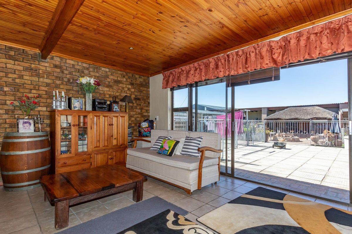 Living room featuring exposed brick walls, a timber-clad ceiling, and large sliding glass doors providing direct access to the outdoor patio area.