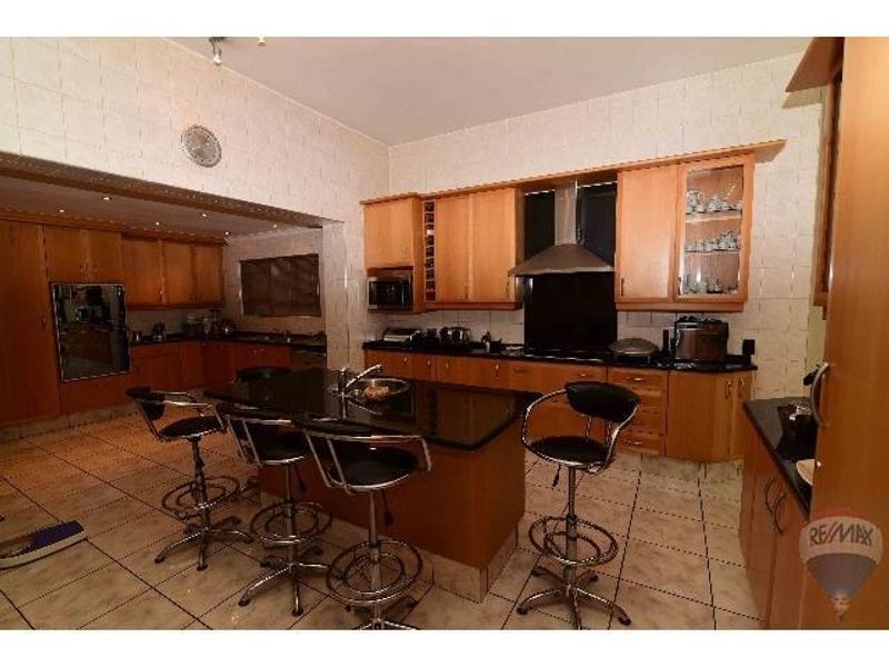 Spacious kitchen featuring light wood cabinetry, a central island with a dark stone countertop, and tiled flooring throughout.