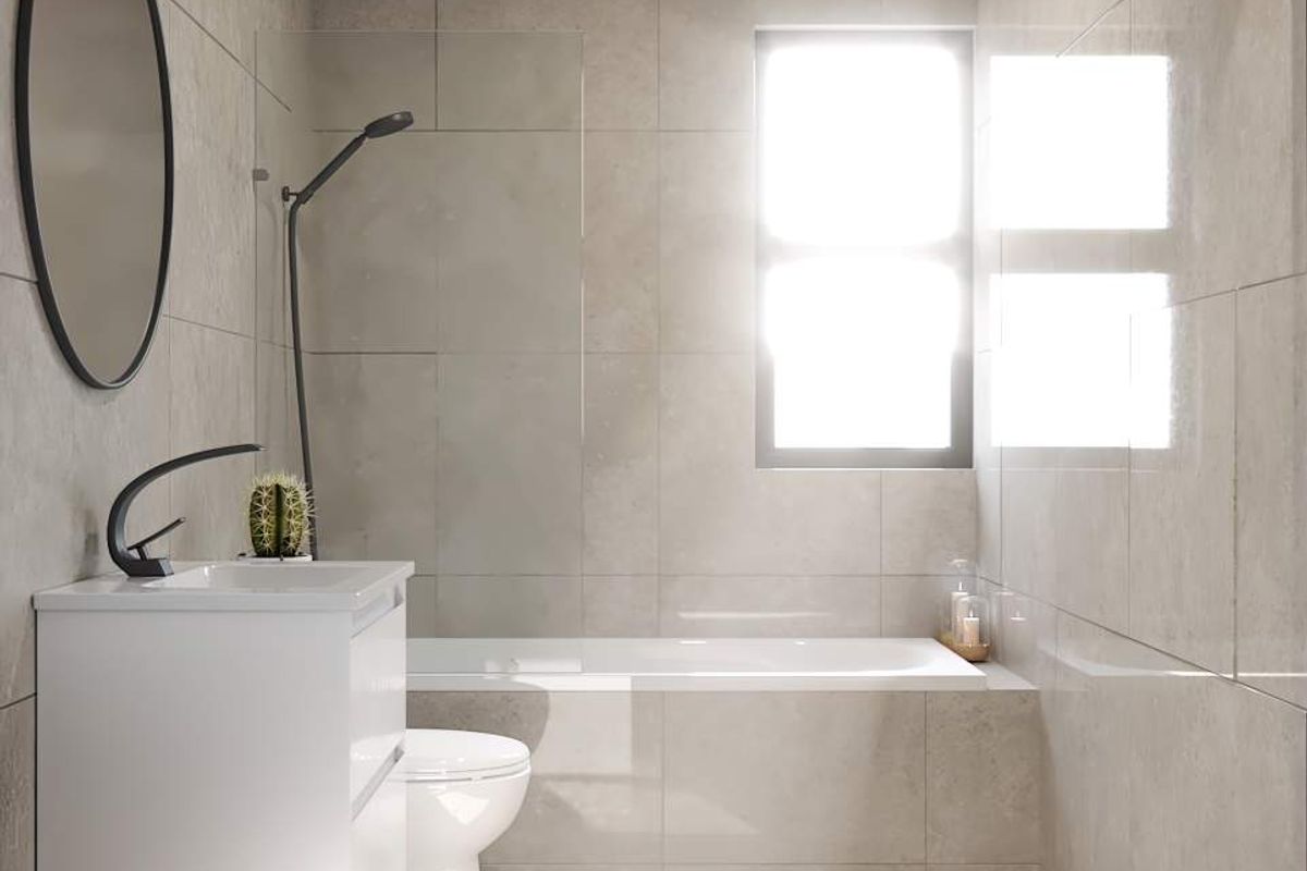 Modern bathroom featuring floor-to-ceiling neutral tiling, a wall-mounted vanity, a bathtub with a glass shower screen, and a window providing natural light.