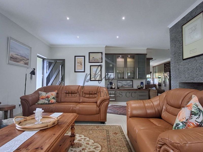 Spacious living room featuring a stone accent wall, recessed downlighting, and custom built-in cabinetry, creating a warm and inviting atmosphere.