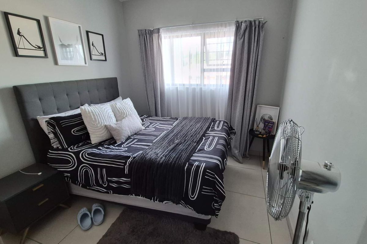 A well-maintained bedroom featuring neutral wall finishes, tiled flooring, and a window with curtain tracks.