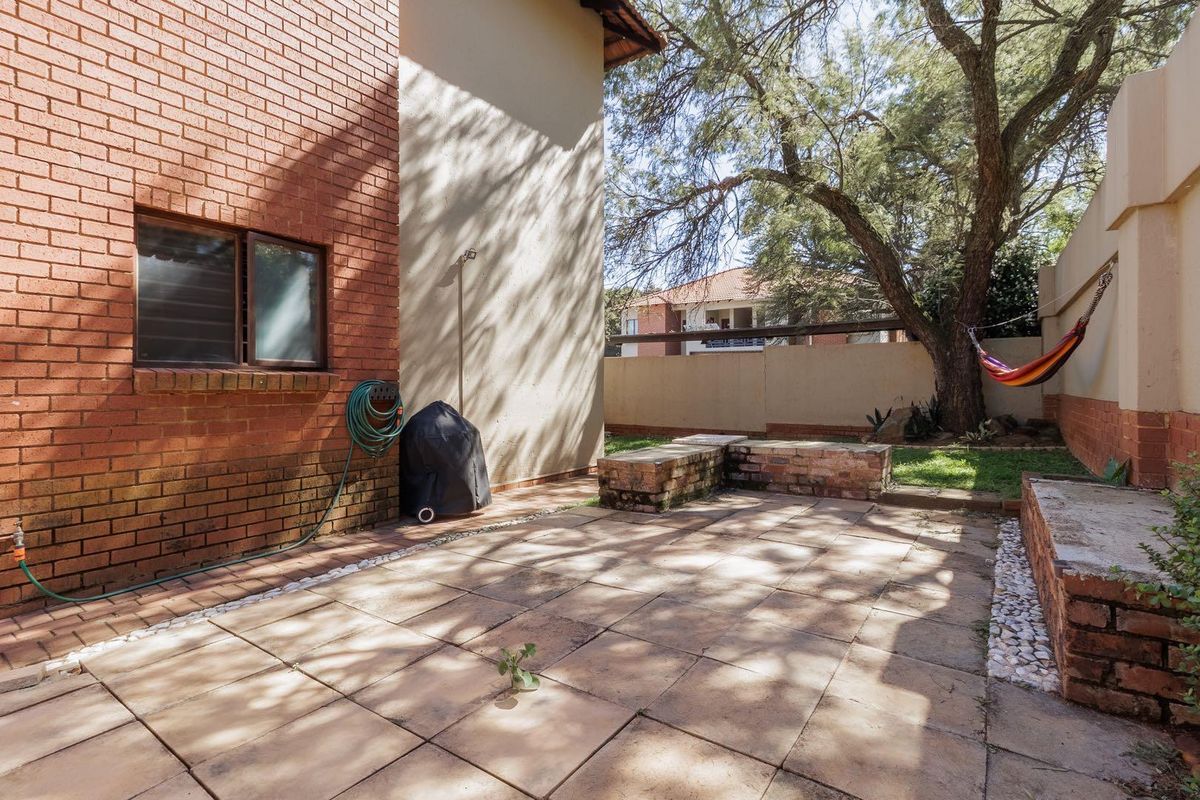 A private rear courtyard featuring paved flooring, built-in brick seating, and a mature tree, providing a functional outdoor space for the townhouse.