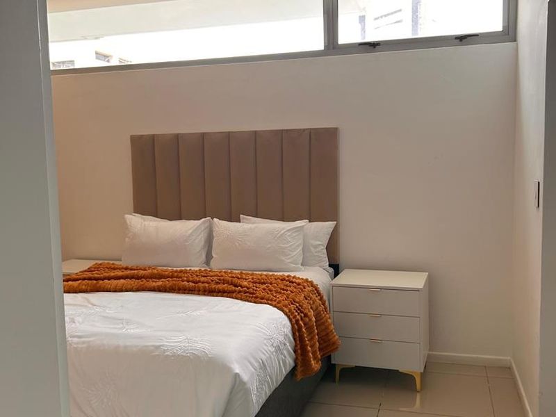 A well-lit bedroom featuring neutral tiled flooring and high-level clerestory windows that provide natural light while maintaining privacy.