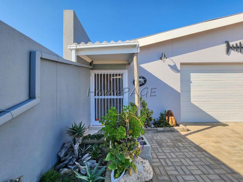 Front entrance area featuring a security gate, paved driveway, and garage access with well-maintained exterior finishes.