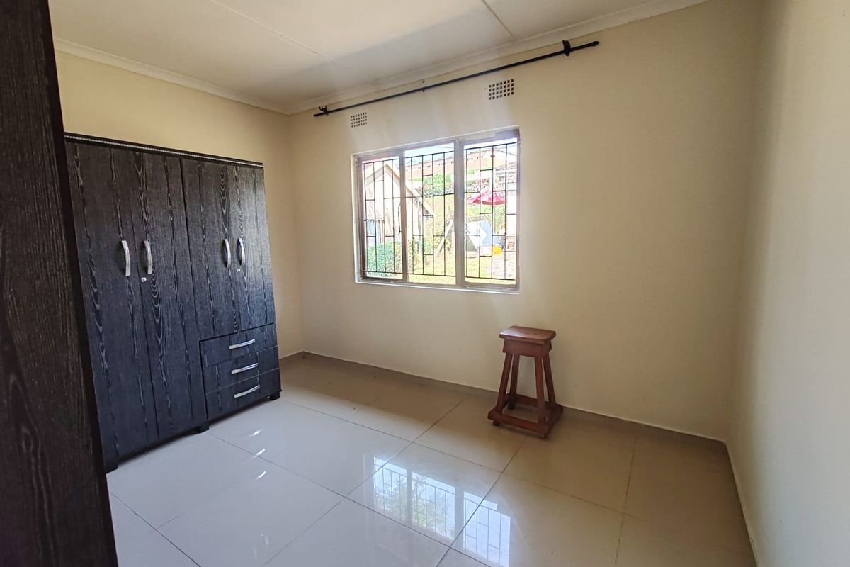 A clean, empty bedroom featuring tiled flooring, a window with security bars, and a neutral wall finish, ready for personalization.