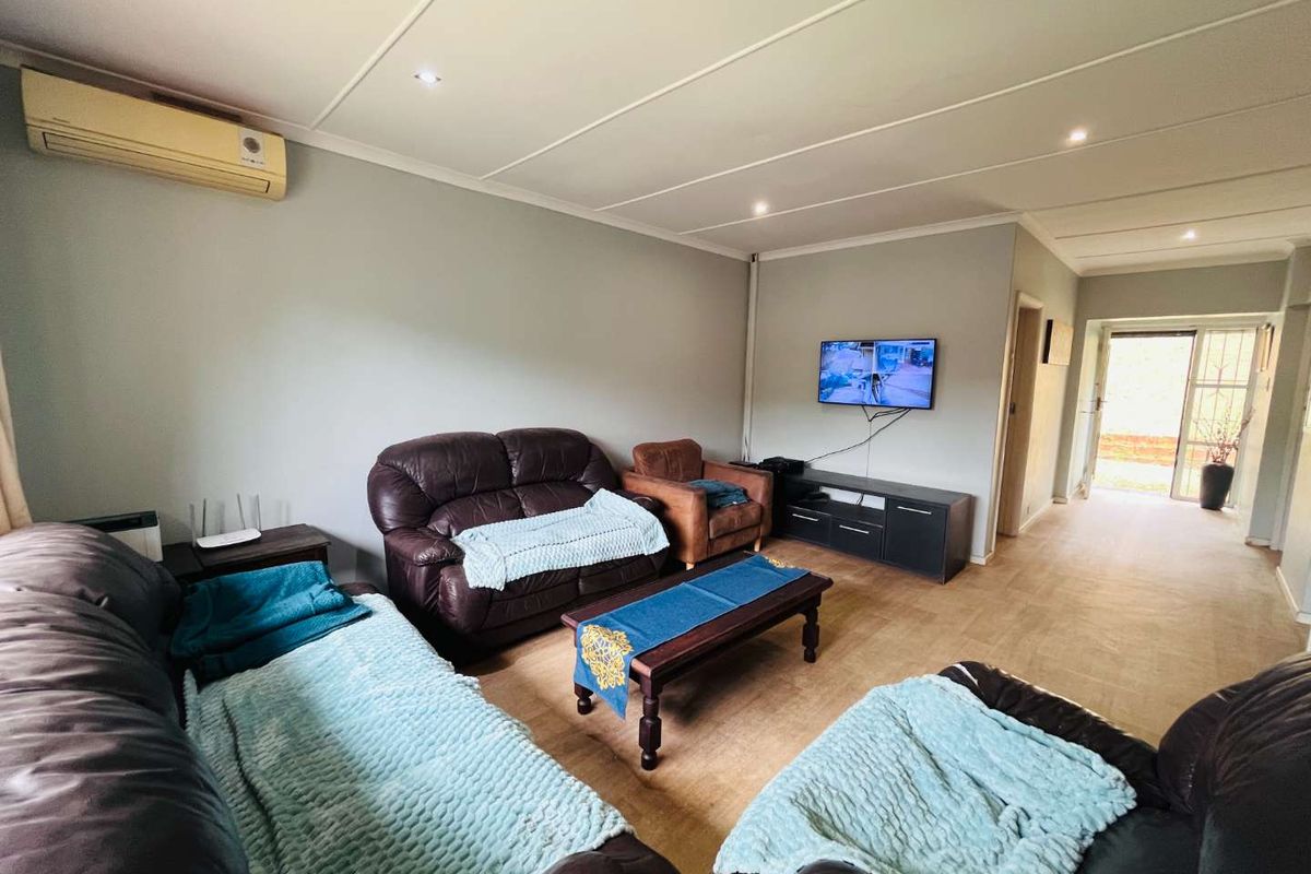 A spacious living room featuring recessed lighting, a wall-mounted air conditioning unit, and direct access to an exterior doorway.